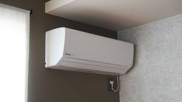 Eine weiße Klimaanlage an einer Wand in einem Raum mit Fenster und einer Wand mit Grau-Struktur.