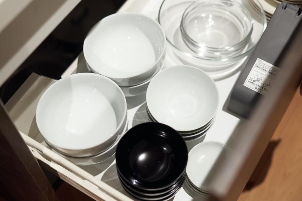 A drawer containing various white and black bowls and plates.