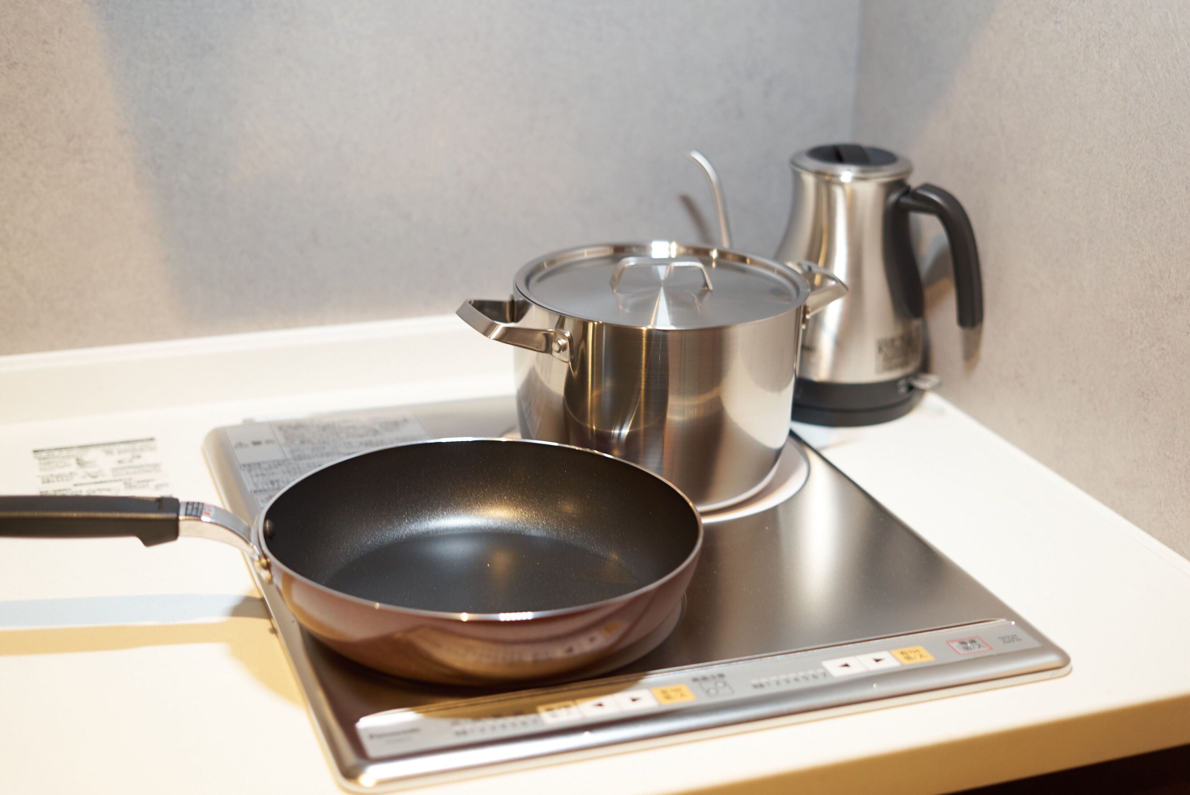 A kitchen with a stove, a frying pan, a pot, and a kettle.