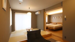A compact hotel room with a bed, a small table, and a futon bed. - NEON HOTEL (Kanazawa)