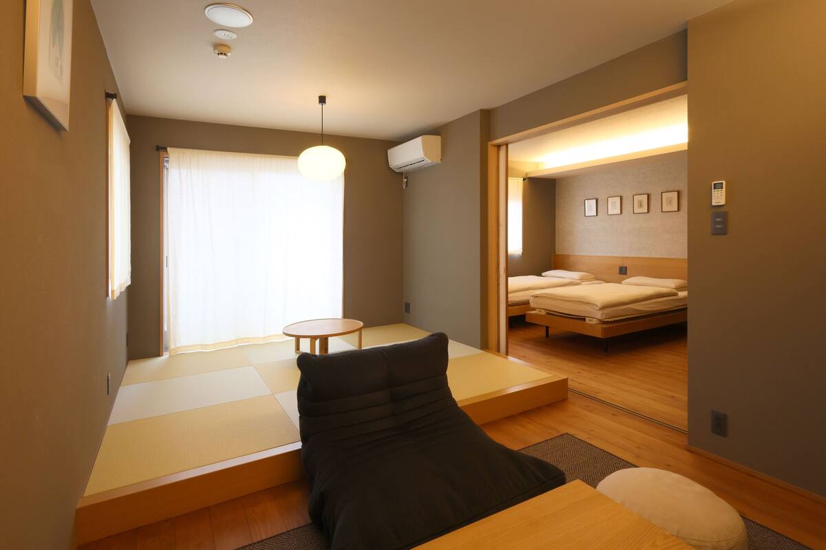 A compact hotel room with a bed, a small table, and a futon bed.