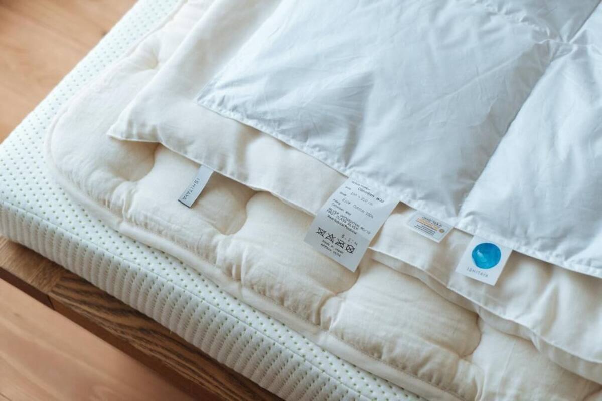 A mattress with a white cover and multiple labels, including a blue tag.