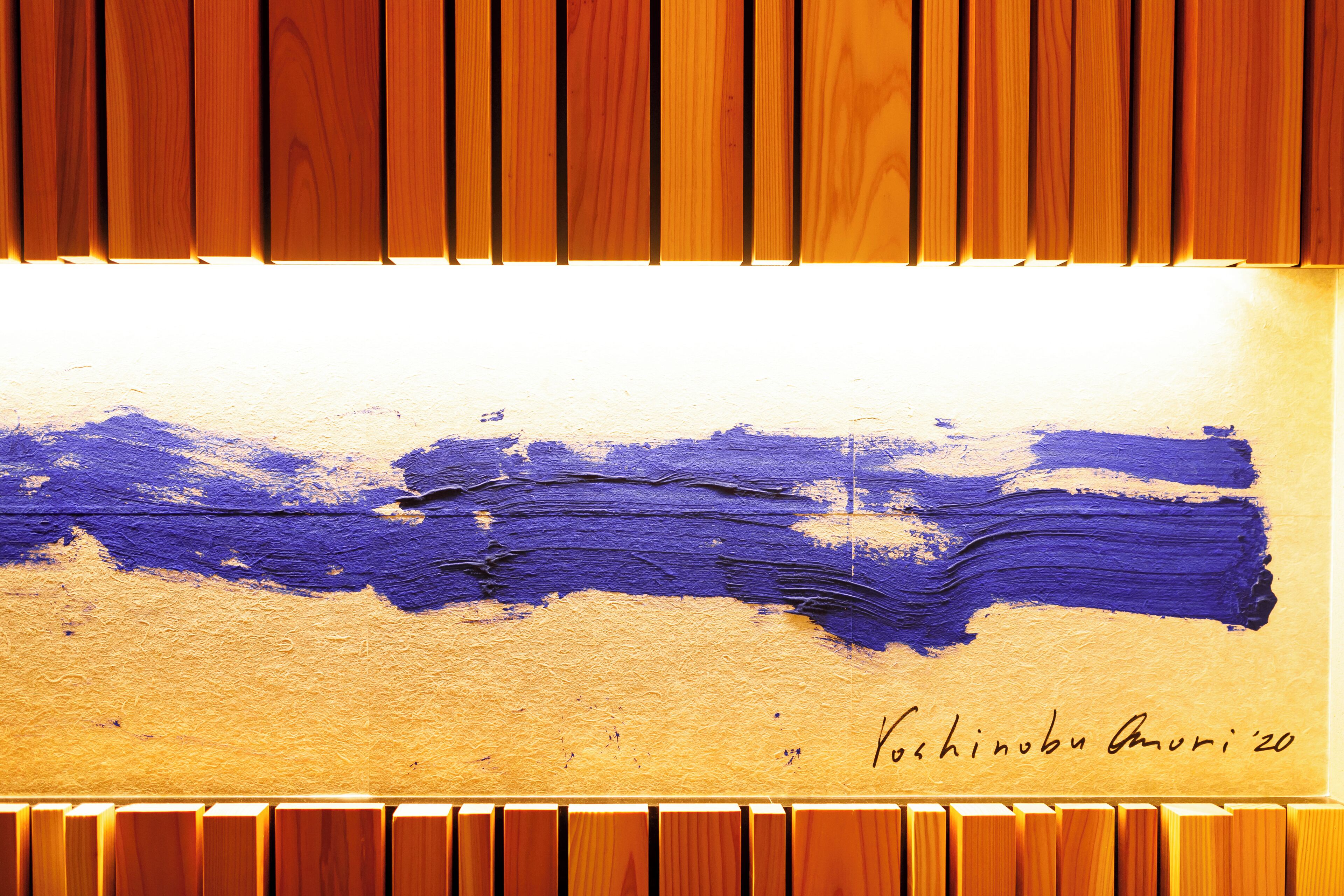 A wooden panel wall with a textured surface and a blue abstract painting.