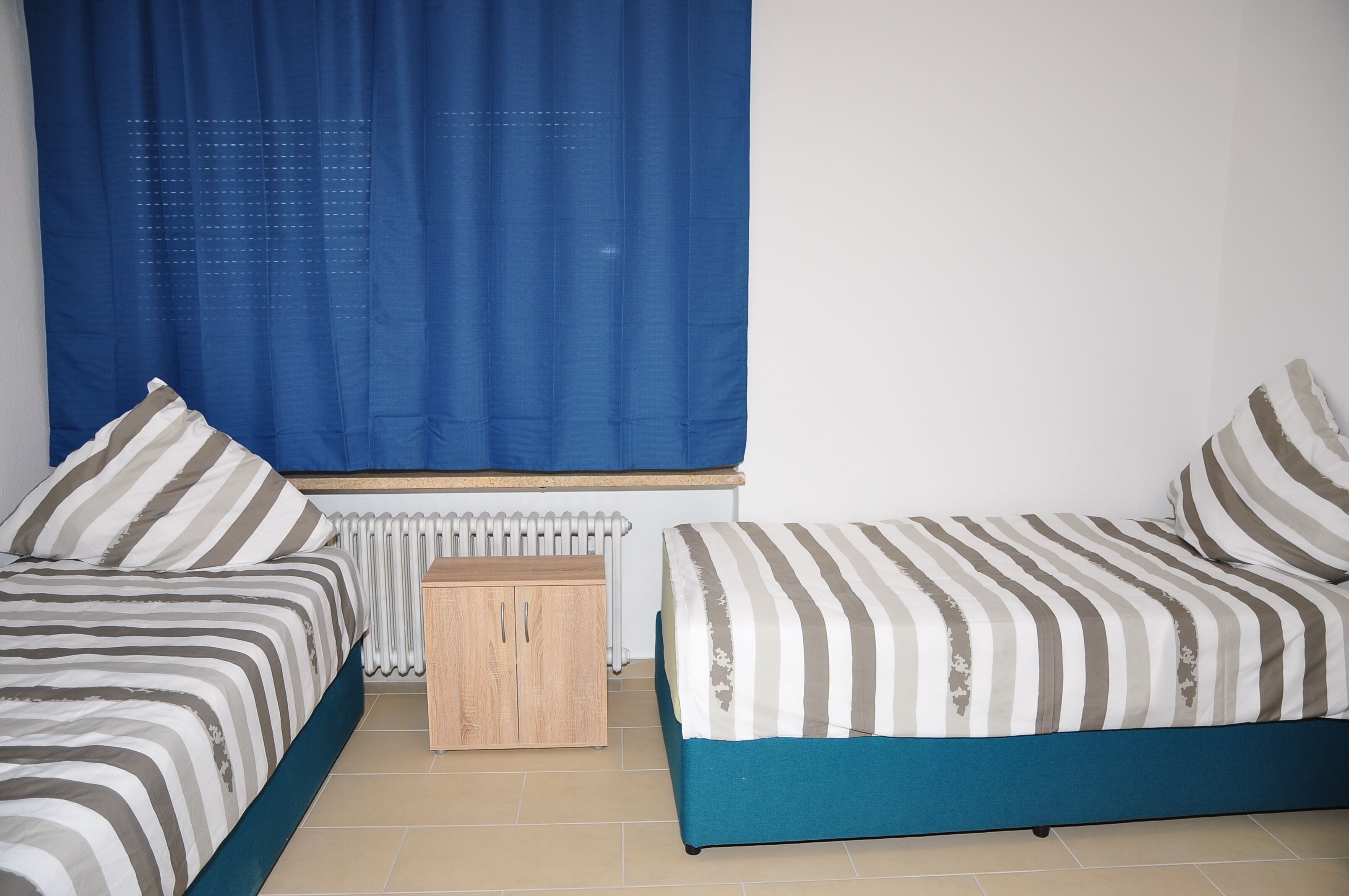 Quarto com duas camas, um armário de madeira e um radiador.