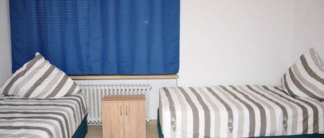 Quarto com duas camas, um armário de madeira e um radiador.