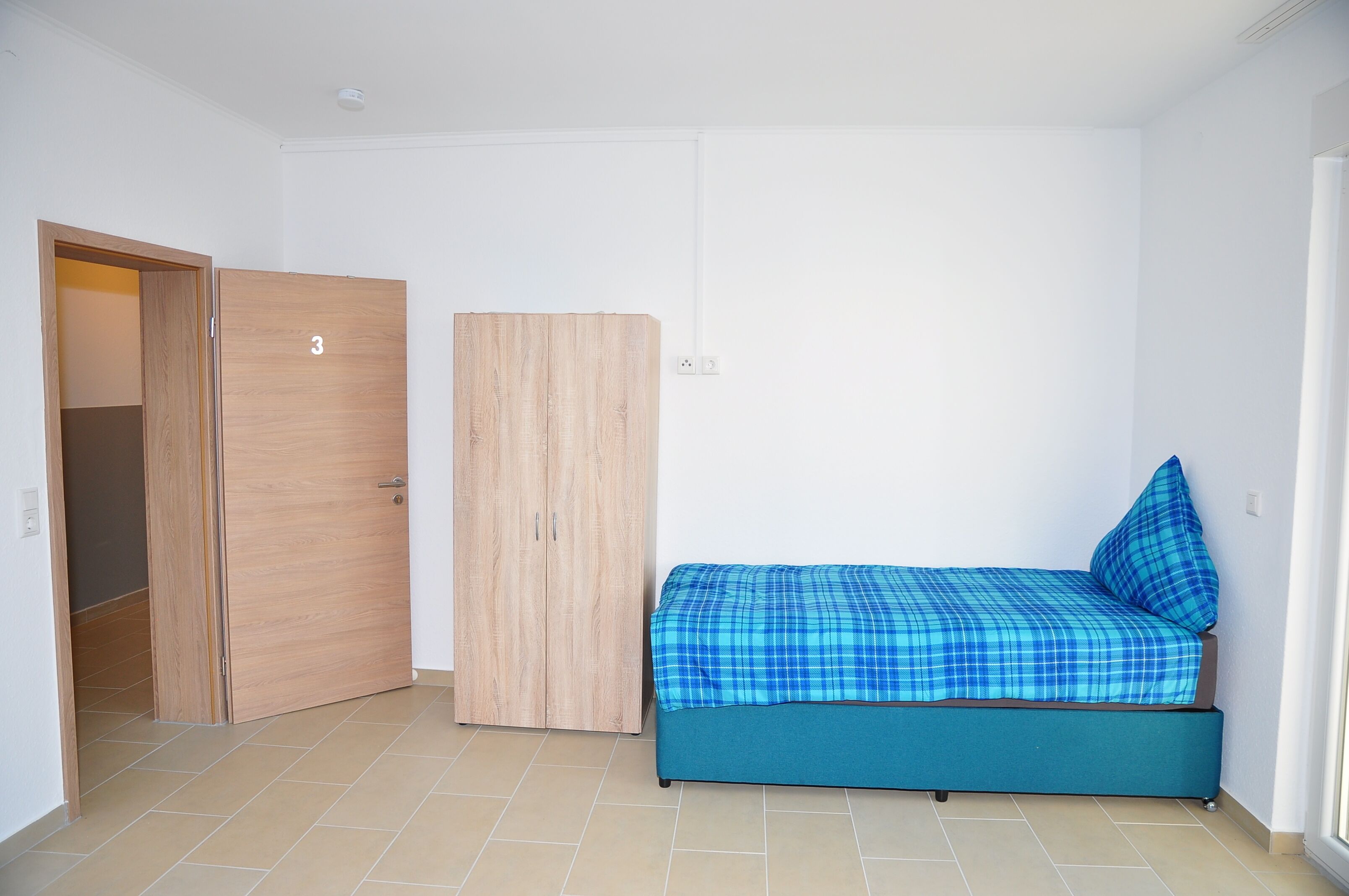 A bedroom with a bed, a wardrobe, and a door.