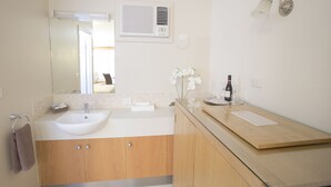 A modern bathroom with a double sink, wooden cabinets, a mirror, an air conditioning unit, and a wall-mounted light fixture. - Horsham Country City Motor Inn (Horsham)