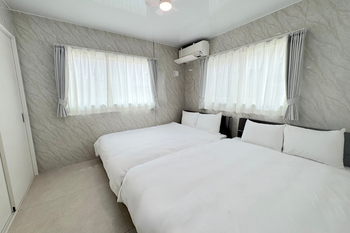 A hotel room with two beds, marble walls, and an air conditioning unit.