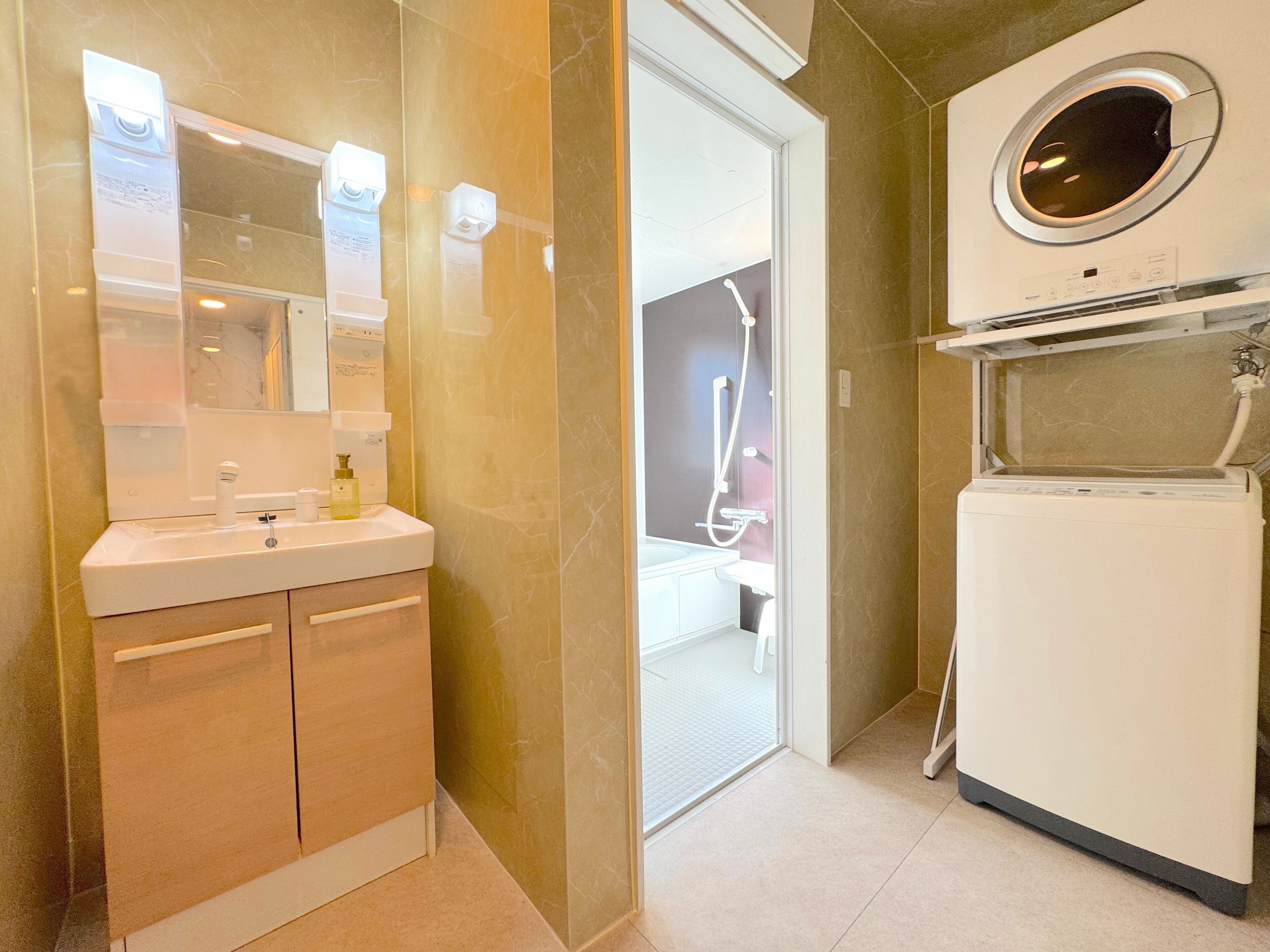 A modern bathroom with a sink, mirror, and built-in washing machine.