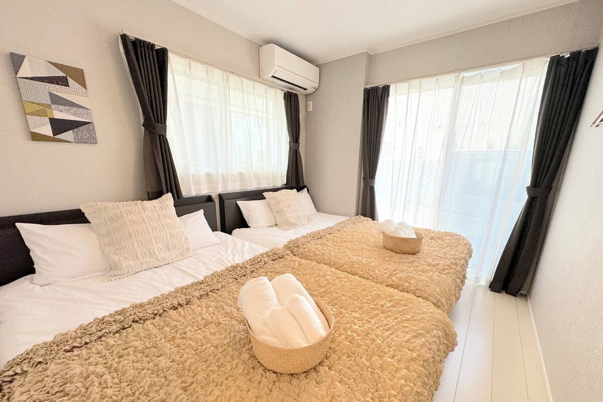 Une chambre d’hôtel avec deux lits, une grande fenêtre et un climatiseur fixé au mur.