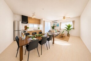 Une cuisine moderne avec un coin repas, un salon doté d’un canapé et un ventilateur de plafond.