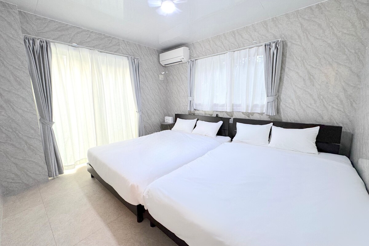 A hotel room with a large bed, two bedside tables, a ceiling fan, and an air conditioning unit.