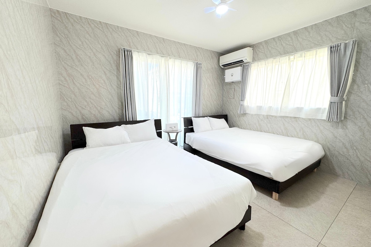 A hotel room with two beds, marble walls, and an air conditioning unit.