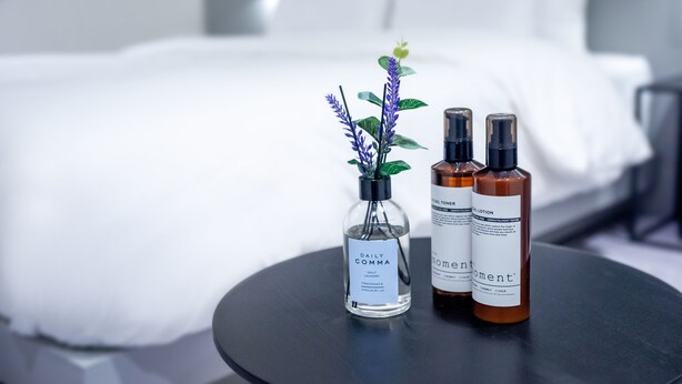 A hotel room with a bed, a small round table, and two bottles of lotion on the table. - Hotel  Yam YeonSan (Busan)