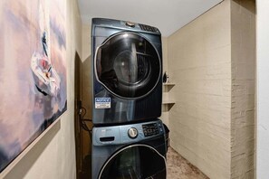A stacked washer and dryer unit in a narrow hallway with a painting on the wall. - Normandy Approach w/Optional Boat Rental (Mooresville)