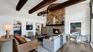 Un salon spacieux doté d’une cheminée en pierre, de poutres en bois et d’une grande fenêtre.