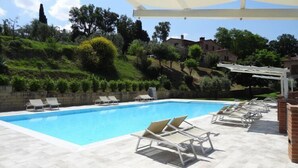 A swimming pool with lounge chairs and a pergola.