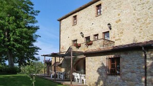 A stone building with a covered patio area, outdoor seating, and a well-maintained lawn.