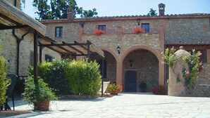 A courtyard with stone flooring, a pergola, and potted plants.