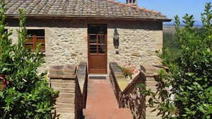 A stone building with a tiled roof, a wooden door, and a small window.