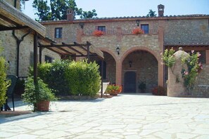 Une cour avec un sol en pierre, une pergola et des plantes en pot.