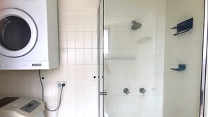 Une salle de bain équipée d’un lave-linge, d’une douche et de toilettes.