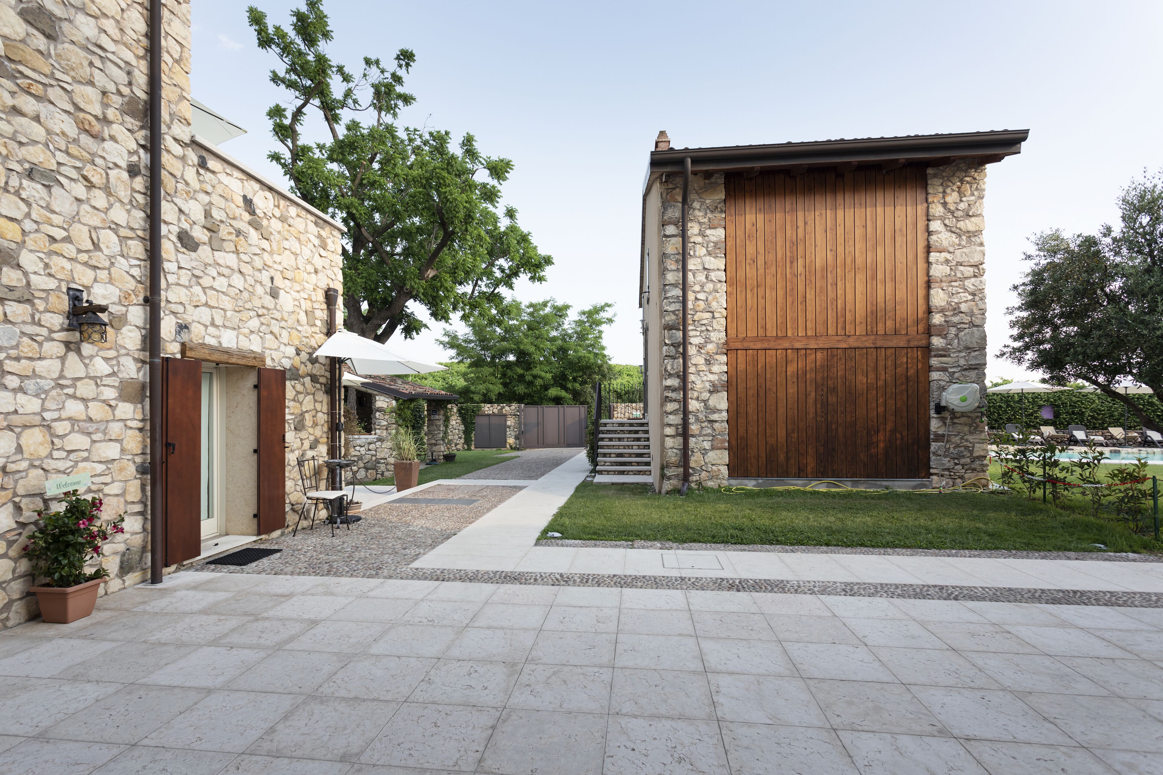 A stone building with a wooden door, a paved walkway, and a small garden area.
