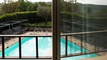 A pool with a metal frame and a view of a landscaped garden through a window.