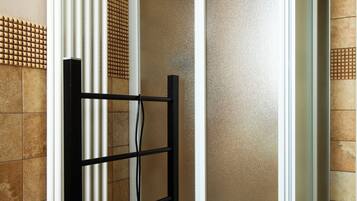 Une salle de bain équipée d’un espace douche, d’un porte-serviettes et d’un radiateur.
