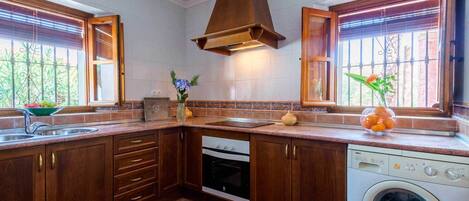 A kitchen with wooden cabinets, a built-in oven, a dishwasher, and a washing machine.