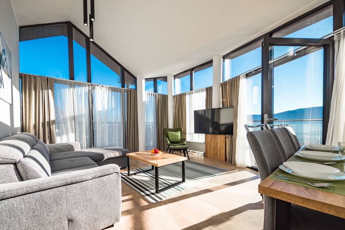 Una habitación de hotel moderna con sofá, mesa de comedor y televisión.