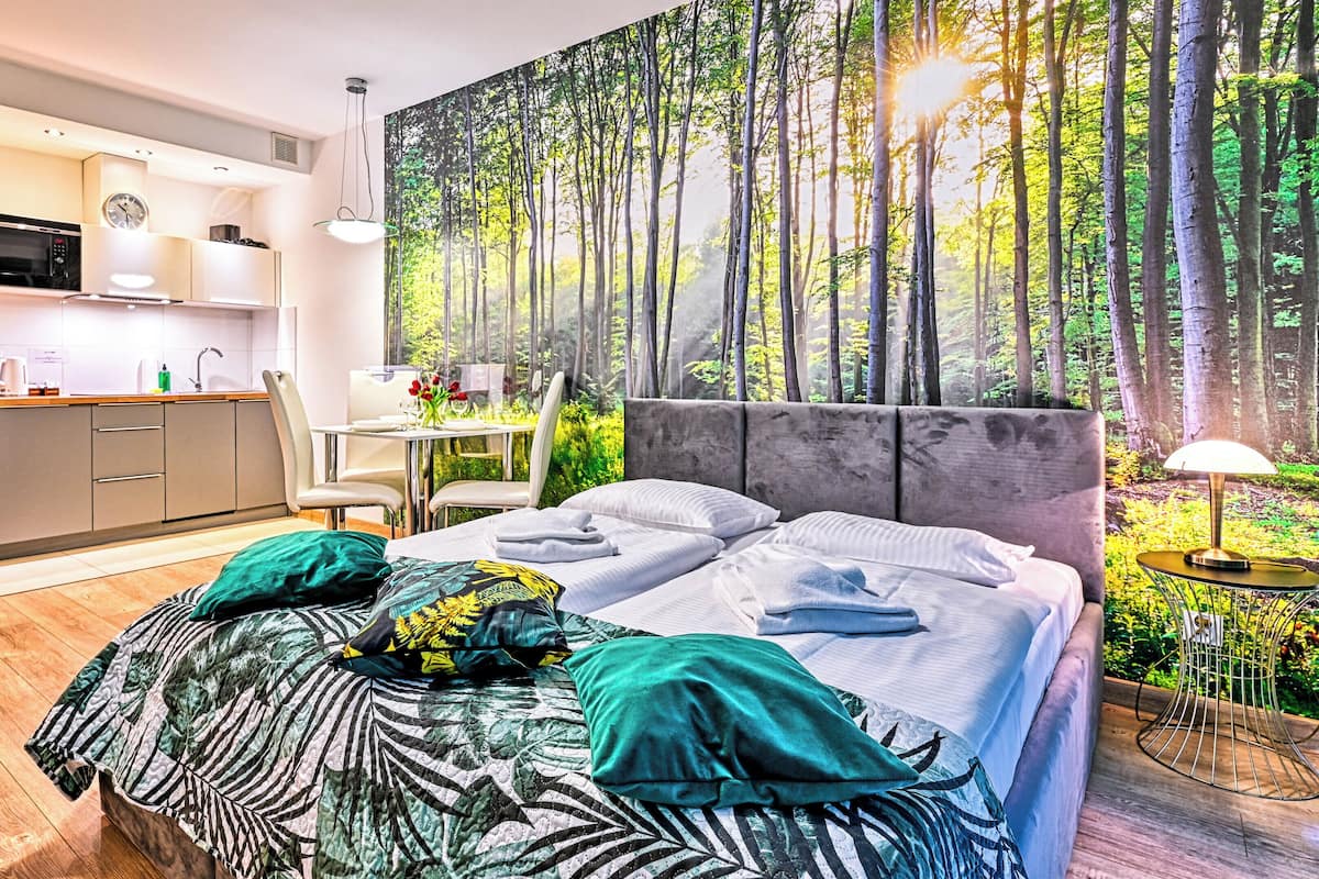 Un dormitorio moderno con una cama grande, un escritorio y una kitchenette.