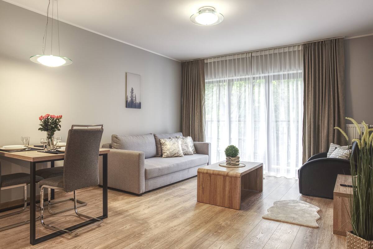 Una sala de estar moderna con comedor, un sofá, una mesa de centro y una planta.