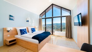 Una camera da letto moderna con un letto grande, una TV e vista sulle montagne.
