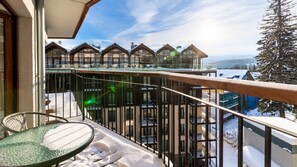 Enjoy the breathtaking view from this balcony with a round table and chair.