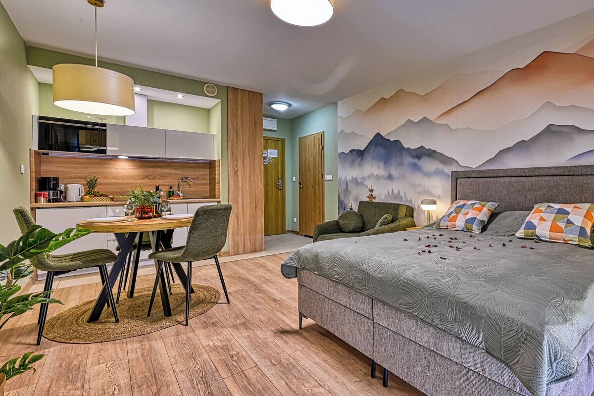 Un dormitorio moderno con una cama grande, un comedor y una cocina.