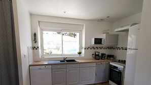 Een moderne keuken met witte kasten, een magnetron, een koffiezetapparaat en een vaatwasser.