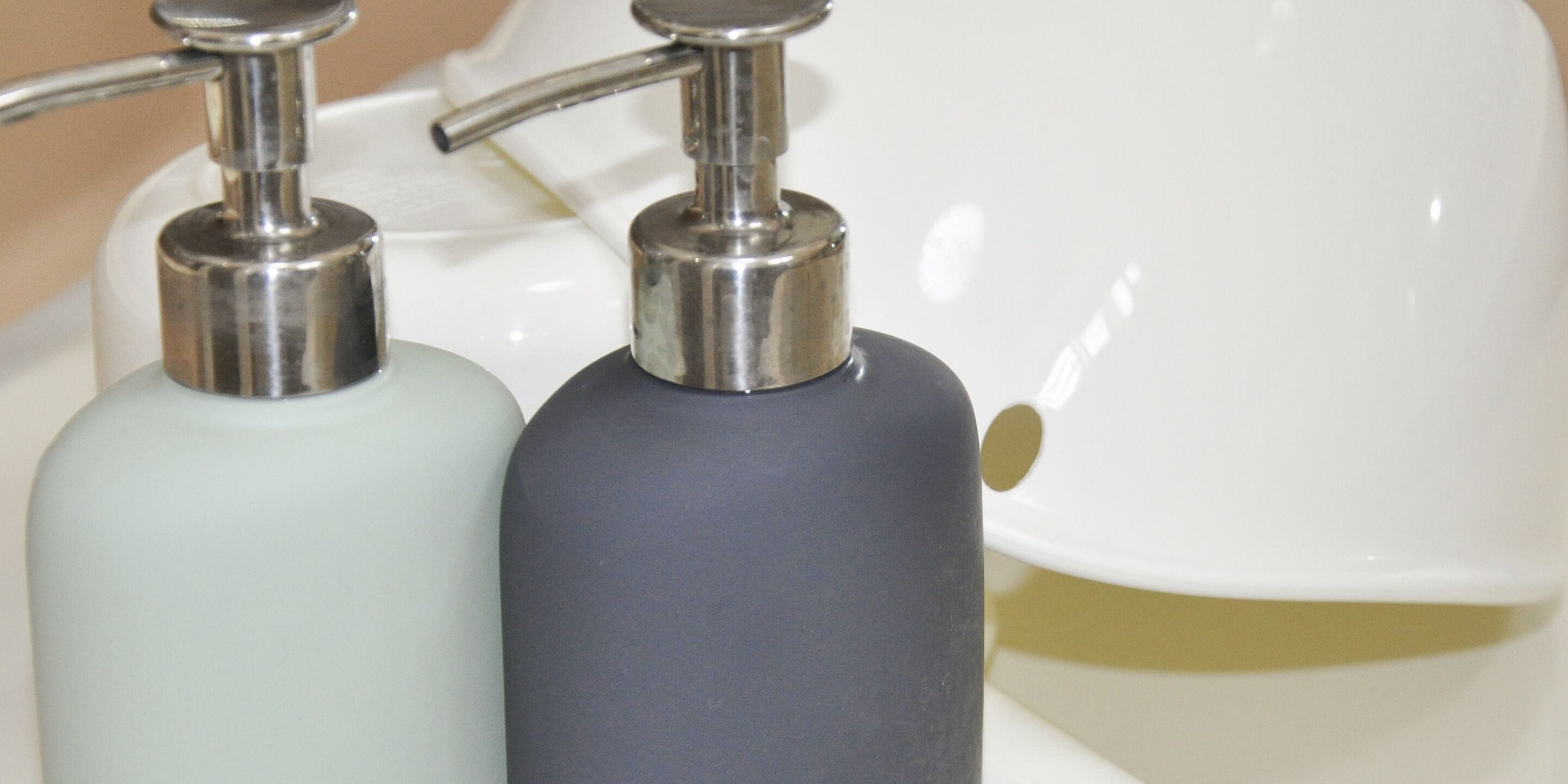 Two soap dispensers on a white sink.