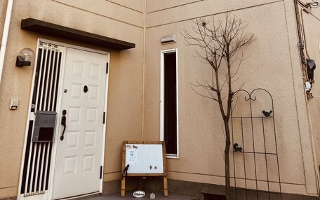A beige building with a white door, a small window, and a mailbox.
