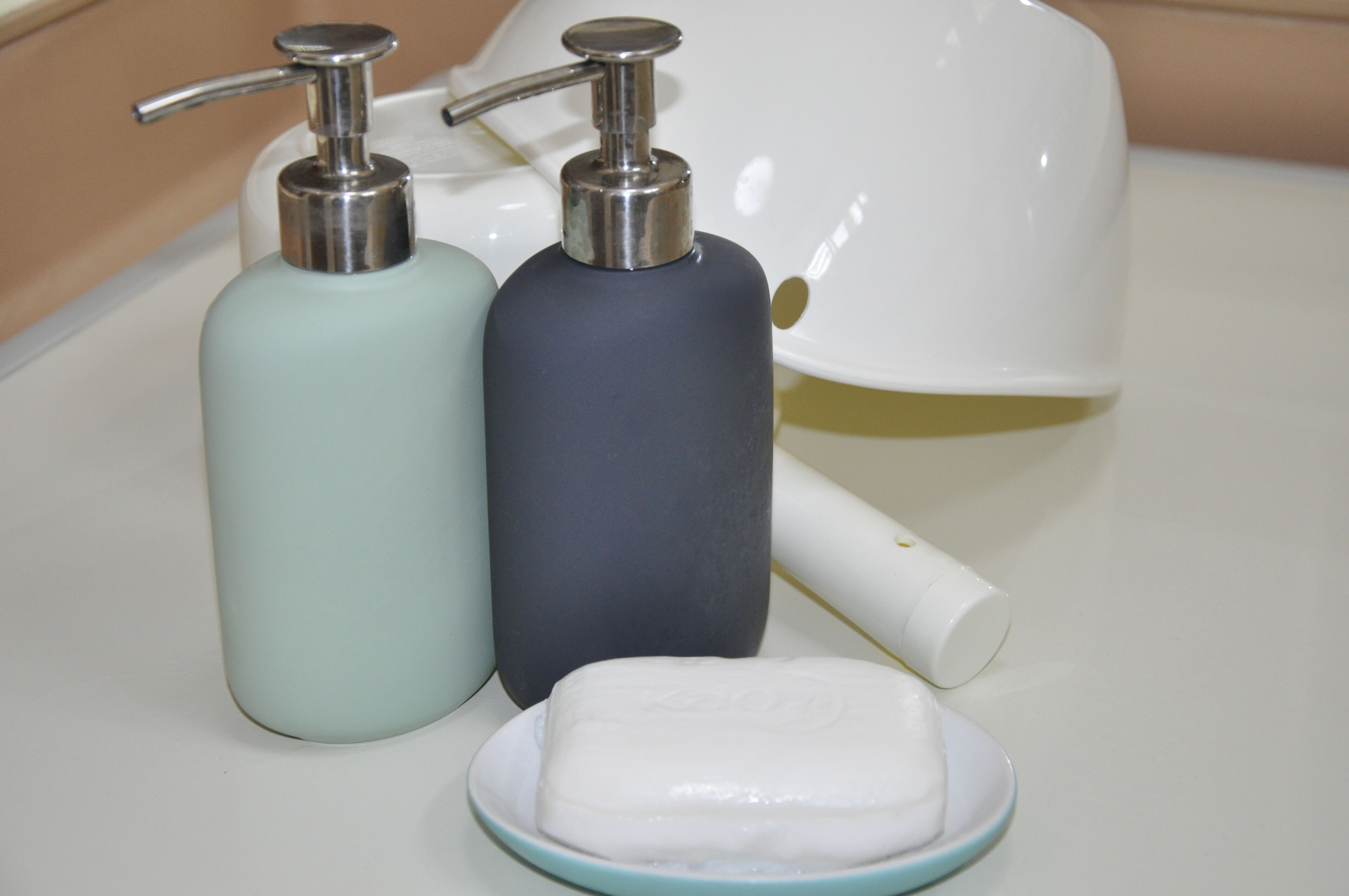 Two soap dispensers and a bar of soap on a countertop.