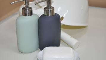 Two soap dispensers and a bar of soap on a countertop.