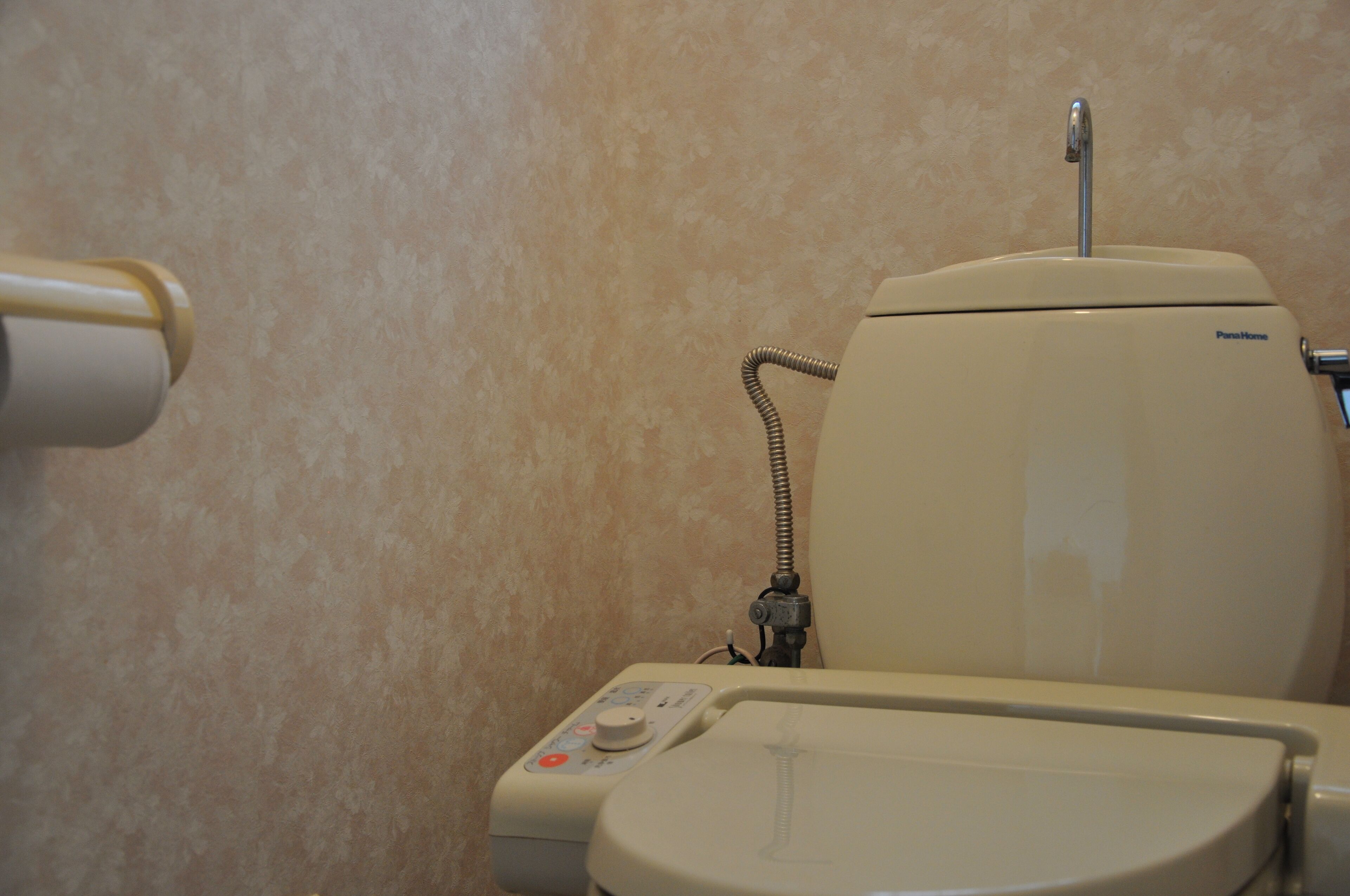 Un inodoro con panel de control y dispensador de papel higiénico.