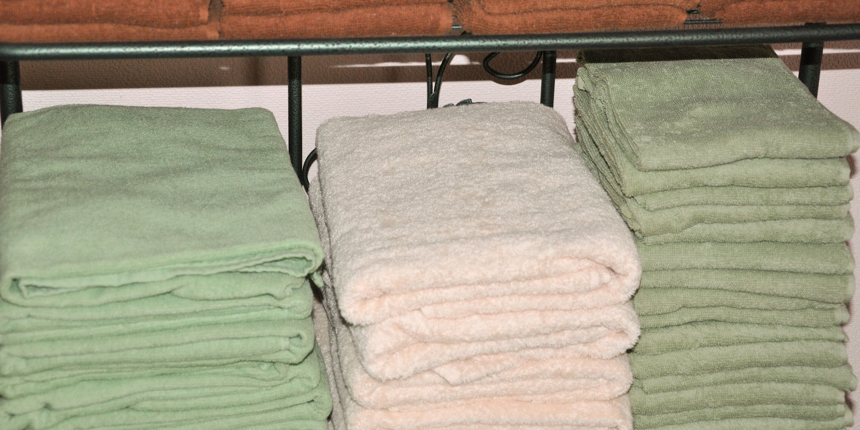 A metal rack with folded towels in green and white colors.