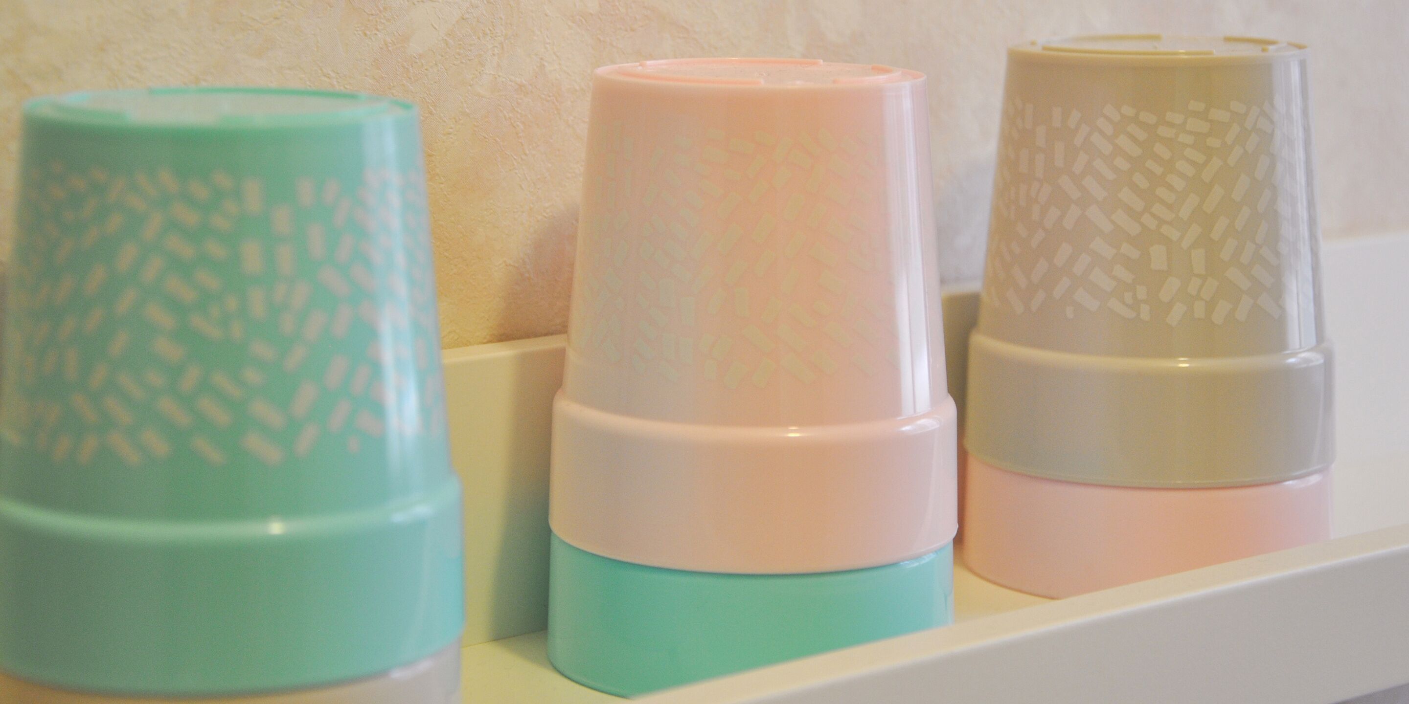 Three stacked containers with textured patterns on a shelf.