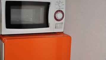 A microwave on top of an orange appliance, possibly a refrigerator.