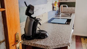 Una cocina con cafetera, lavabo y encimera.