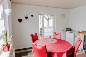 A dining area with a round table, red chairs, a potted plant, and heart-shaped decorations on the wall. - Ferienwohnung Münch (Grossheubach)