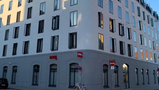 A modern building with multiple windows and a bicycle parked in front.