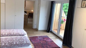 Een slaapkamer met een groot bed, een rood tapijt met een patroon en een schuifdeur naar een balkon.