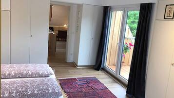 Ein Schlafzimmer mit einem großen Bett, einem roten Teppich mit Muster und einer Glastür, die auf einen Balkon führt.